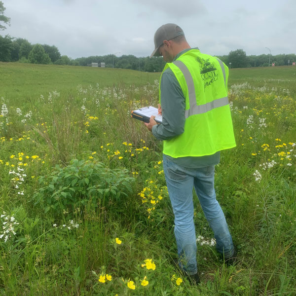 Biologist in field writing on clipboard
