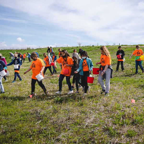 Community members walking and working through field with buckets